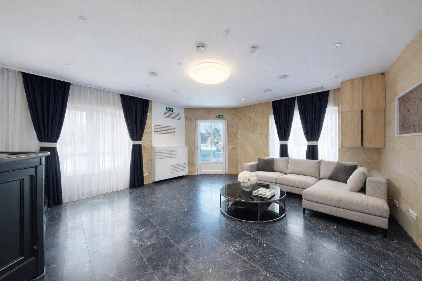 Helle Lobby mit elegantem Marmorboden, beigen Steinwänden und bequemer Sitzecke.