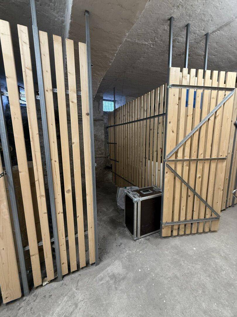 Kellerabteile mit Holzlattenwänden und Betonboden in einem Lagerraum.