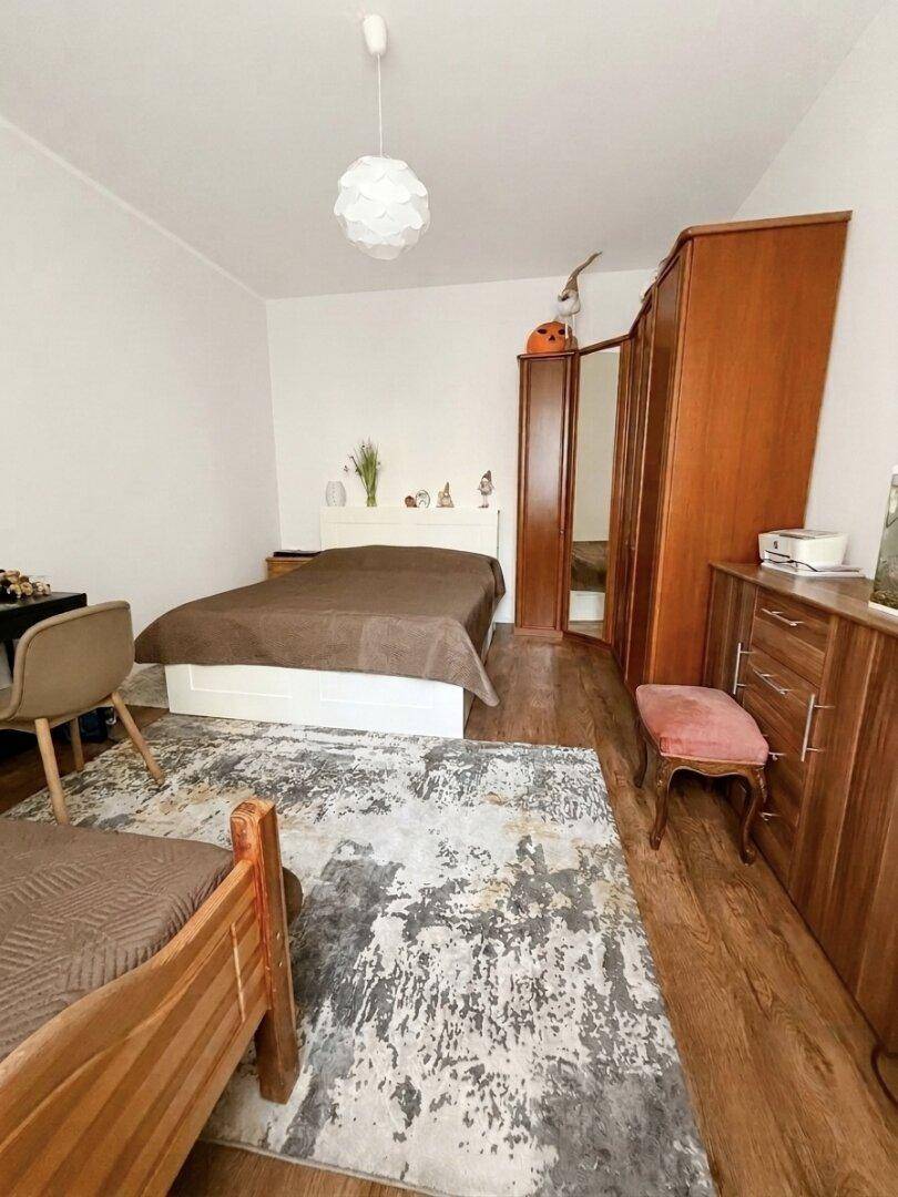 Schlafzimmer mit Doppelbett, Holzboden und großem Kleiderschrank in warmen Holztönen.