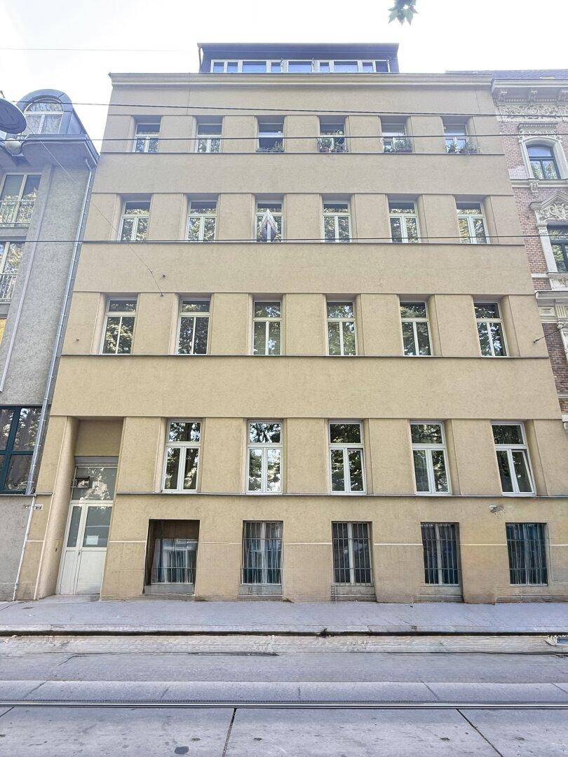 Mehrstöckiges Wohngebäude mit vielen Fenstern und einfacher Fassadengestaltung an einer Straße.