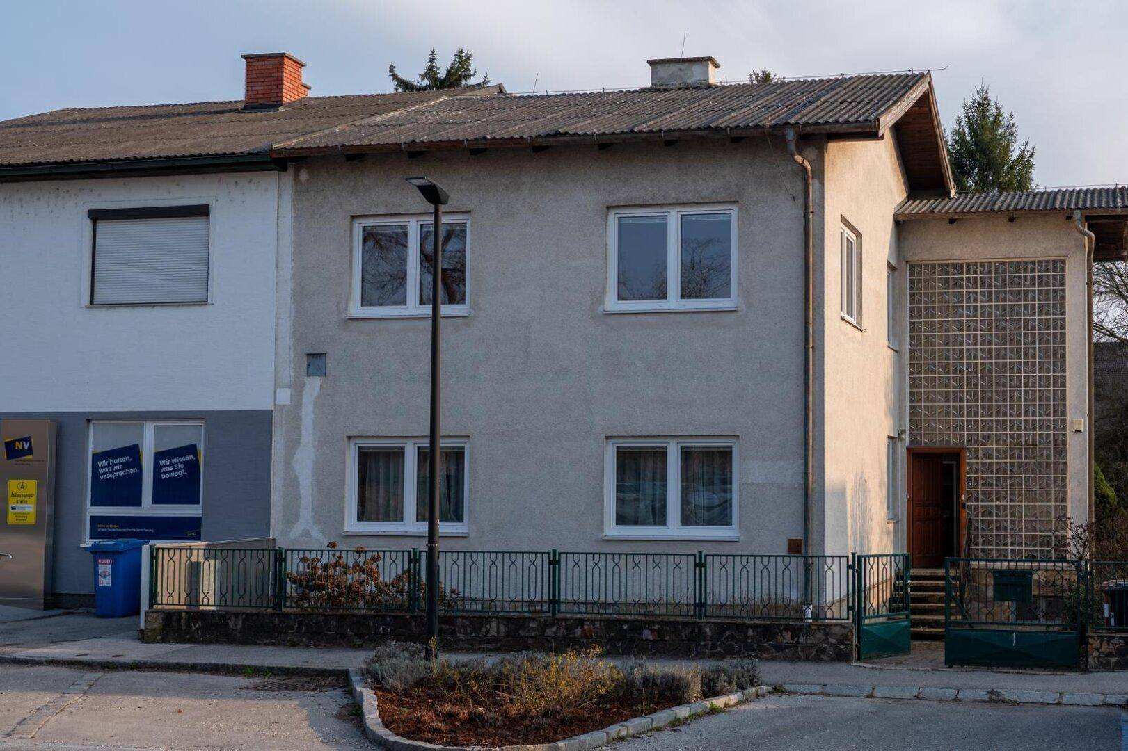 Vorderansicht des Hauses mit mehreren Fenstern und einem kleinen Vorgartenbereich.
