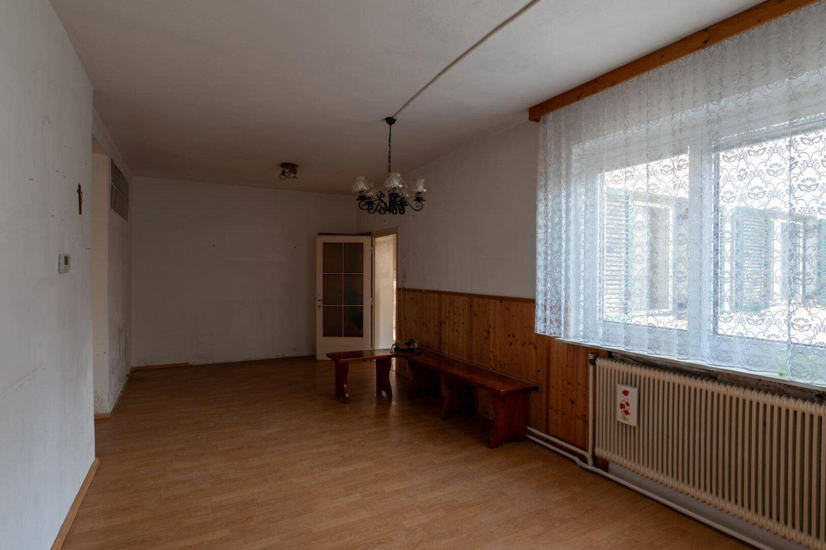 Geräumiges Wohnzimmer mit Laminatboden, Holzvertäfelung und einem großen Fenster.