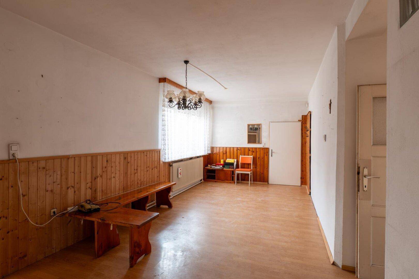 Helles Wohnzimmer mit Laminatboden, Holzvertäfelung und traditioneller Beleuchtung.