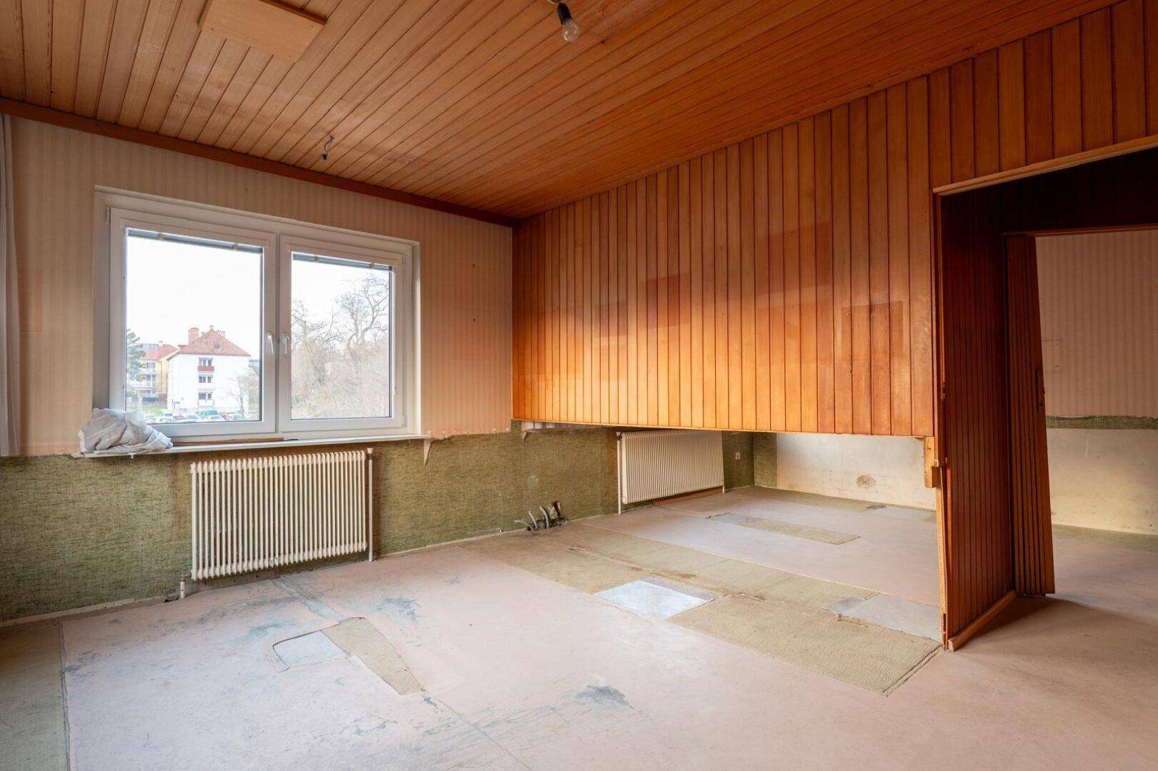Geräumiger Innenraum mit Holzvertäfelung an Wänden und Decke, bereit für eine Renovierung.
