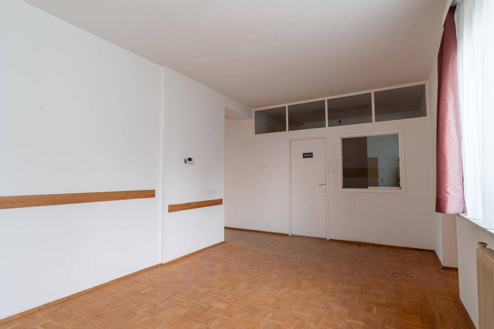 Heller Flur mit Parkettboden, Fenster und Oberlichtern über der Tür, bietet viel Tageslicht.
