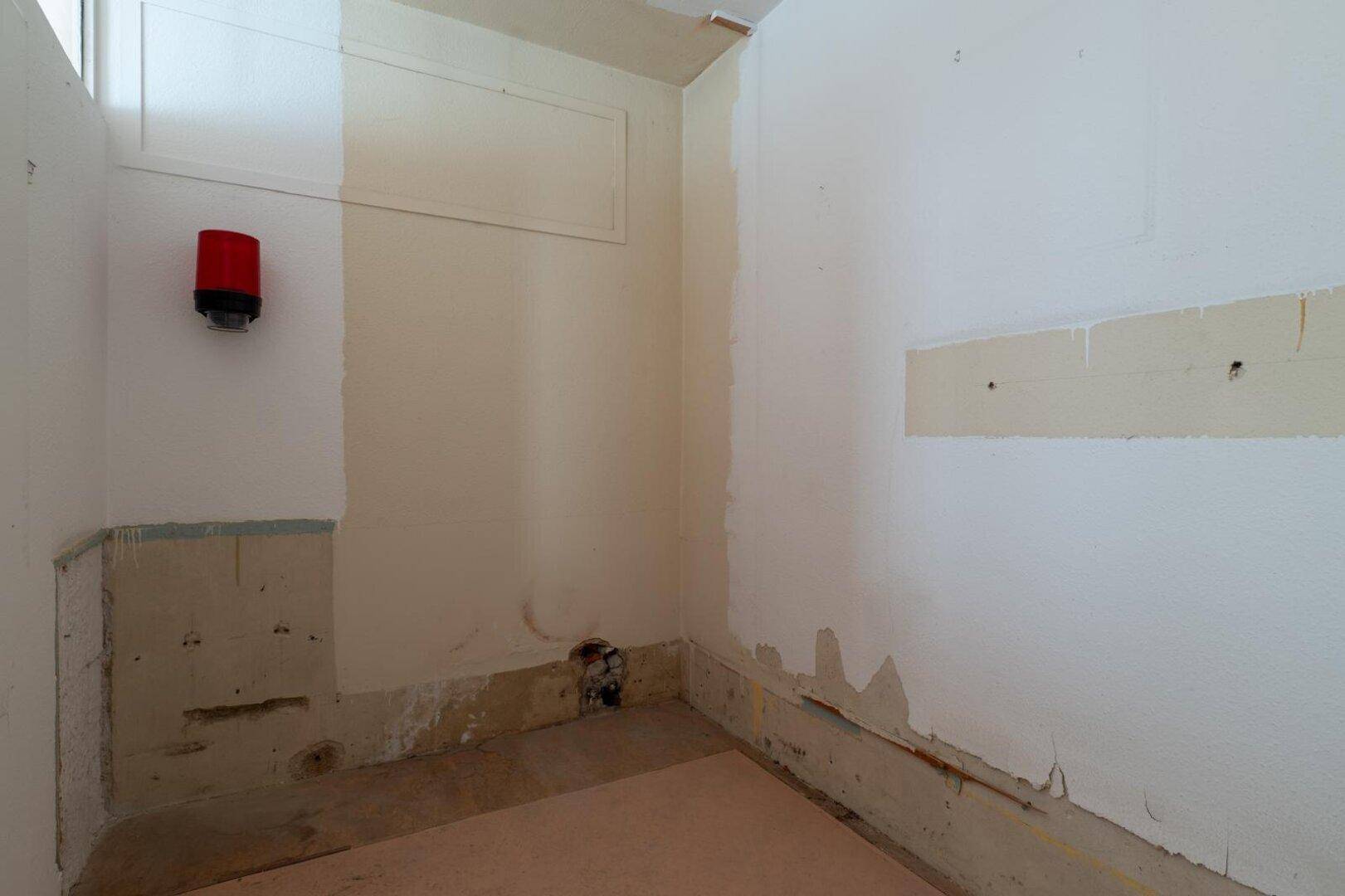 Leerer Raum mit abblätternder Farbe und sichtbaren Leitungen, ideal als Abstellraum.