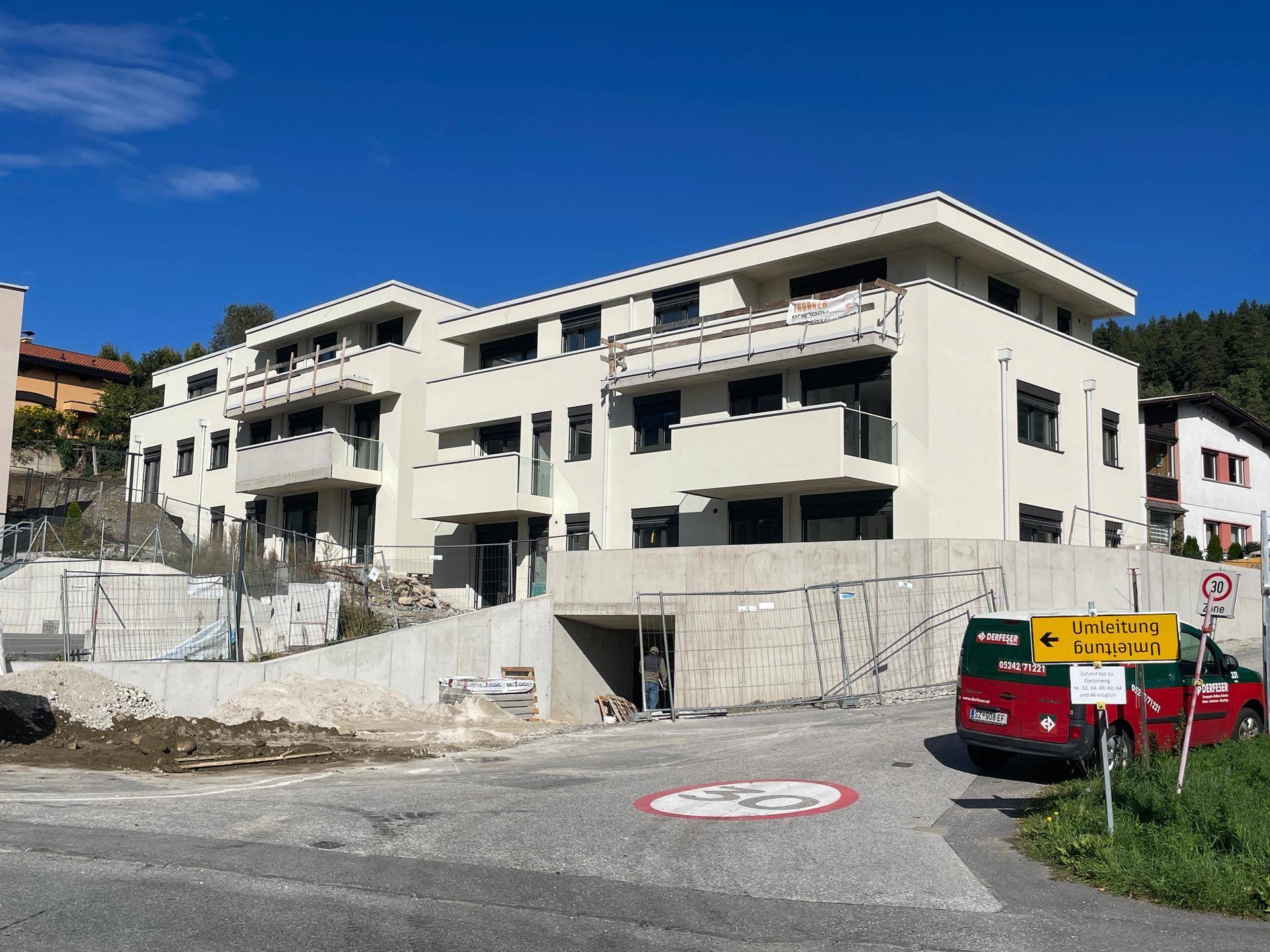 Neubau-Wohngebäude mit moderner Architektur, Balkonen und Zufahrt zur Tiefgarage.