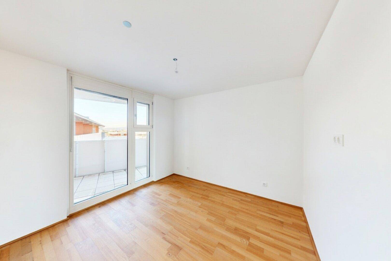Helles Schlafzimmer mit Holzboden und direktem Zugang zu einem privaten Balkon.