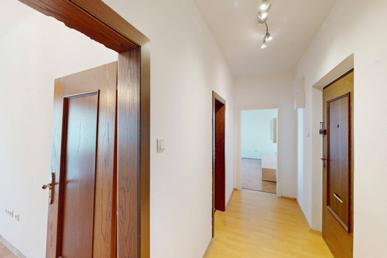 Heller Flur mit Parkettboden und mehreren Holztüren zu den angrenzenden Räumen.