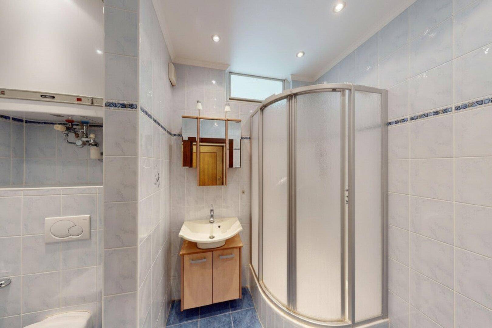 Badezimmer mit blauen und weißen Fliesen, Duschkabine und kleinem Fenster.