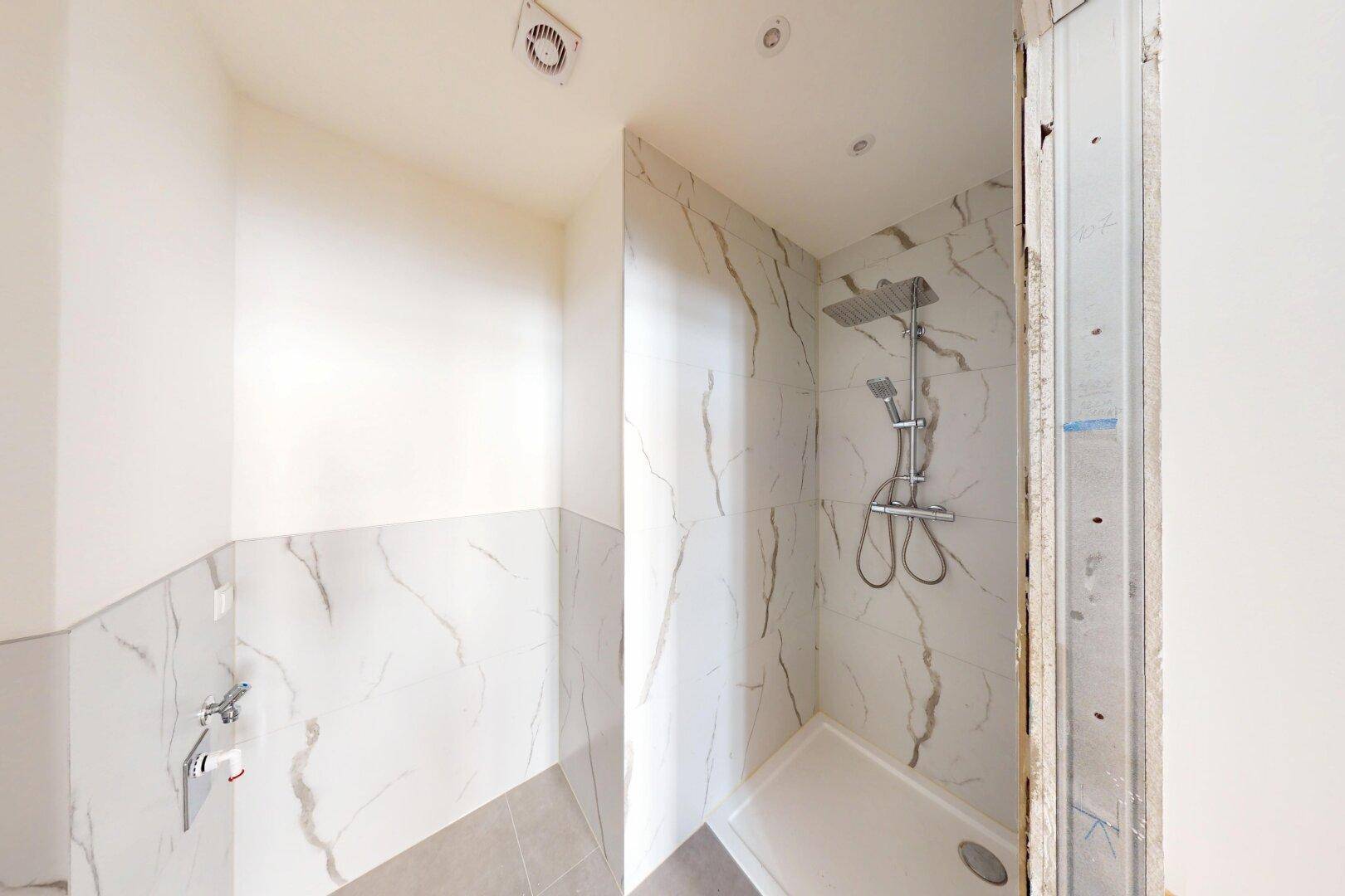 Moderne Duschkabine mit eleganten Marmoroptik-Fliesen und einer Regendusche.