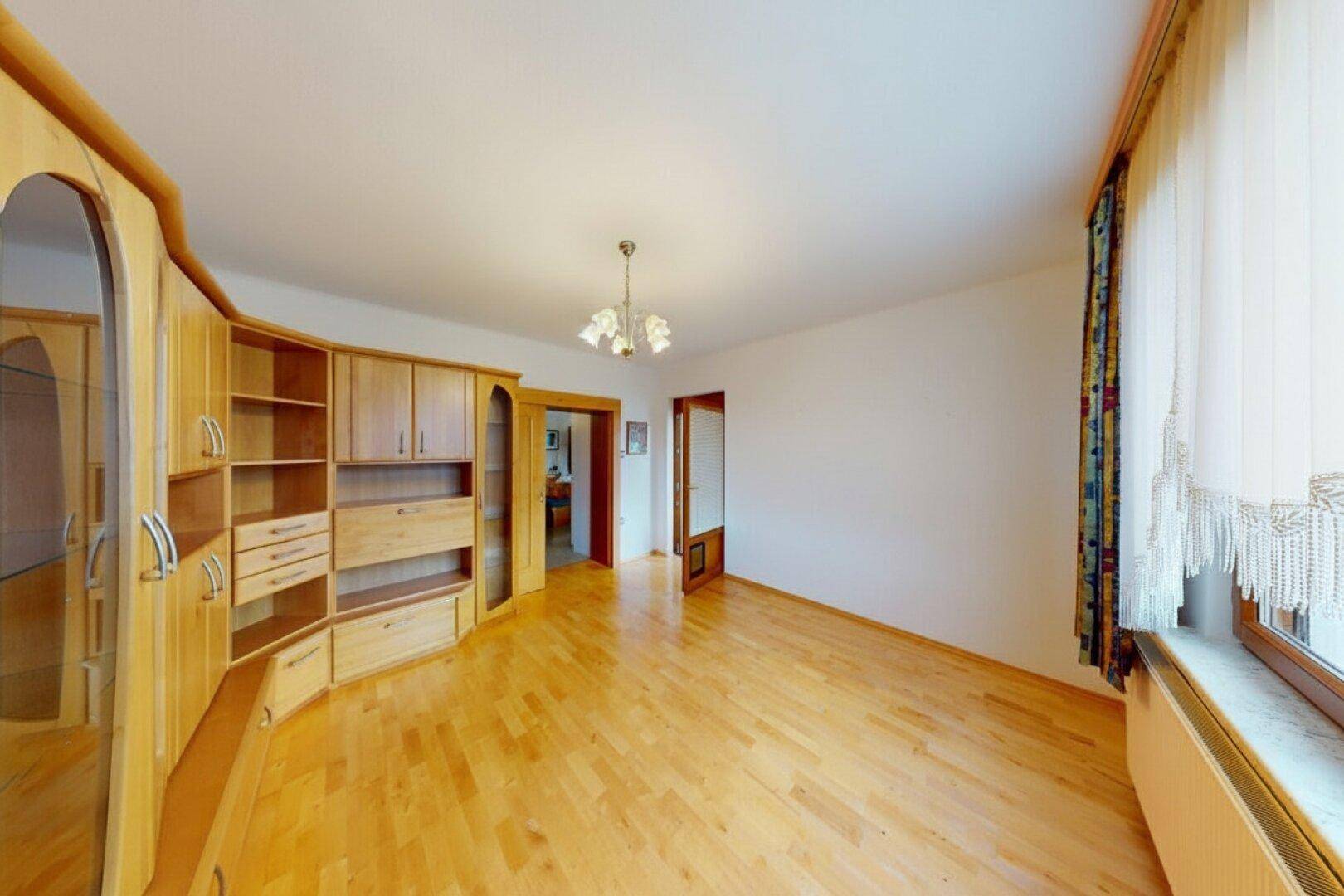 Helles Wohnzimmer mit Holzboden und großem Wandschrank, bereit zur individuellen Gestaltung.