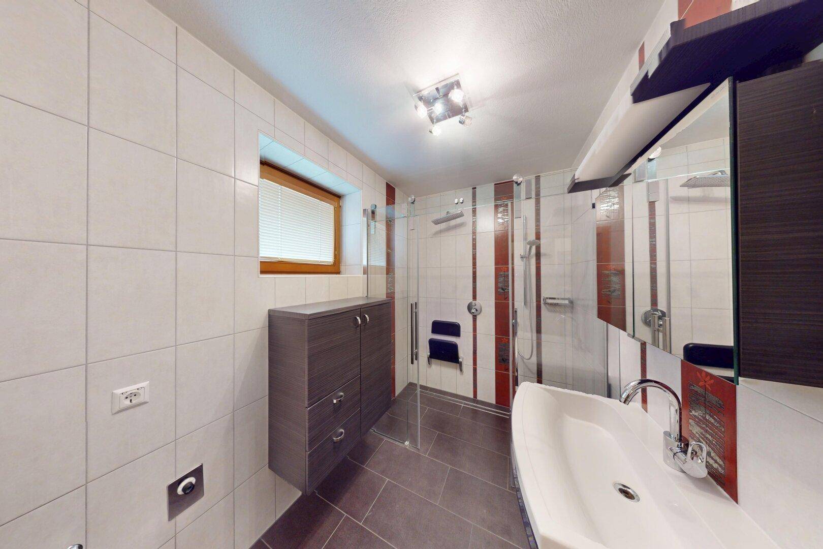 Modernisiertes Badezimmer mit Dusche, Fliesen und Fenster für Tageslicht.