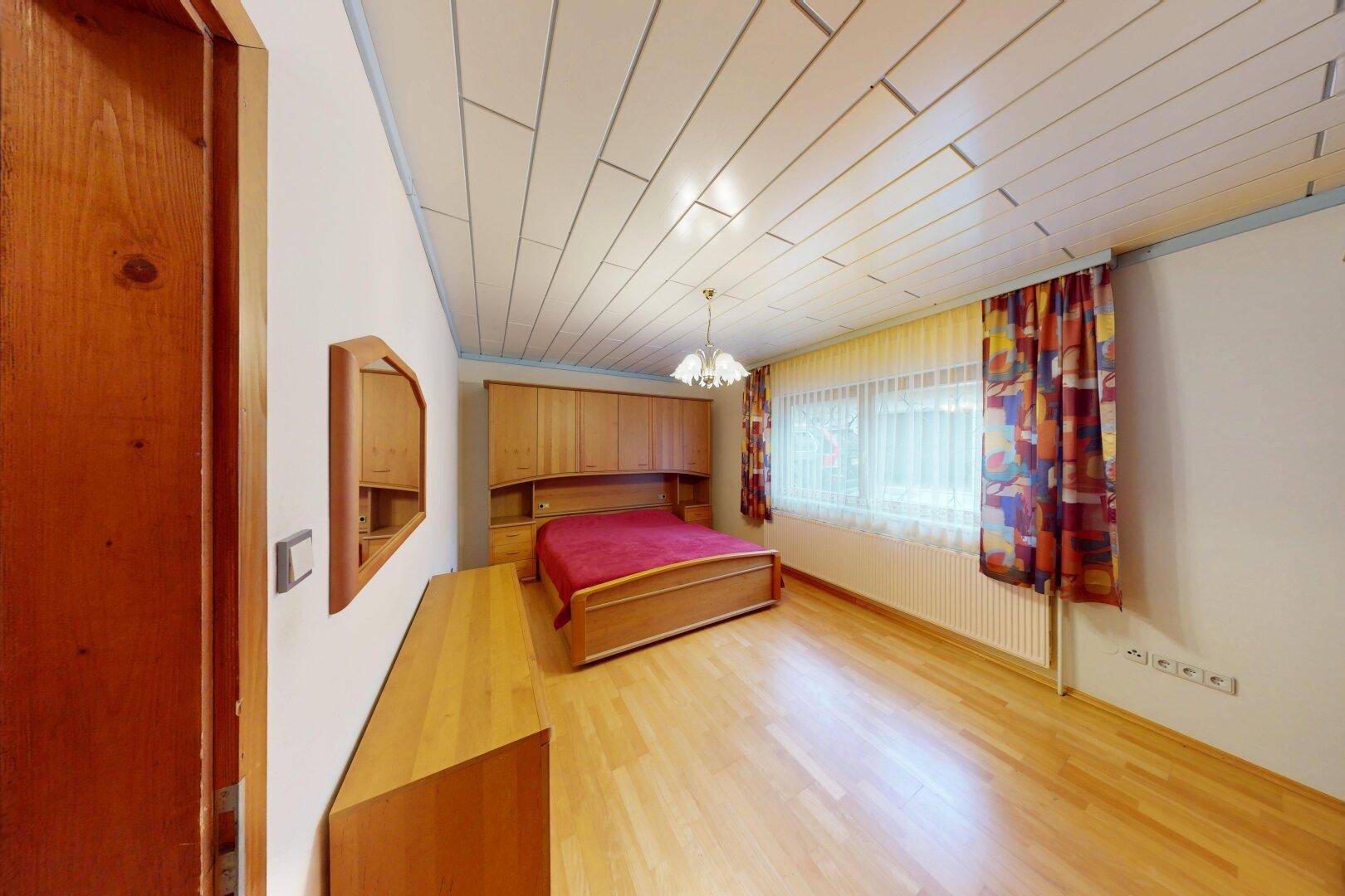Schlafzimmer mit Holzboden, Holzdecke und traditionellen Holzmöbeln.