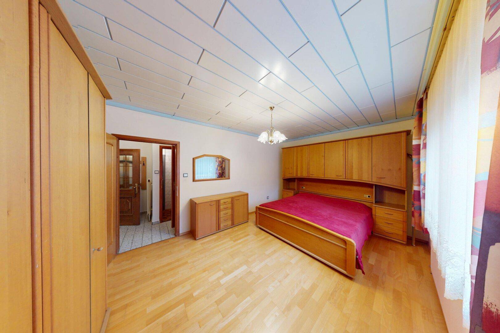 Geräumiges Schlafzimmer mit Holzboden, Holzdecke und großem Kleiderschrank.