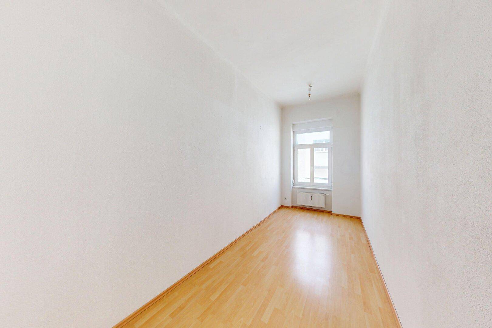 Schmaler, heller Raum mit Parkettboden und einem Fenster, ideal als Schlaf- oder Arbeitszimmer.