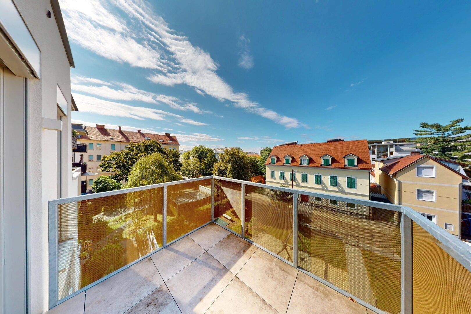 Geräumiger Balkon mit Glasgeländer und Fliesenboden, bietet einen weiten Blick über die Stadt.