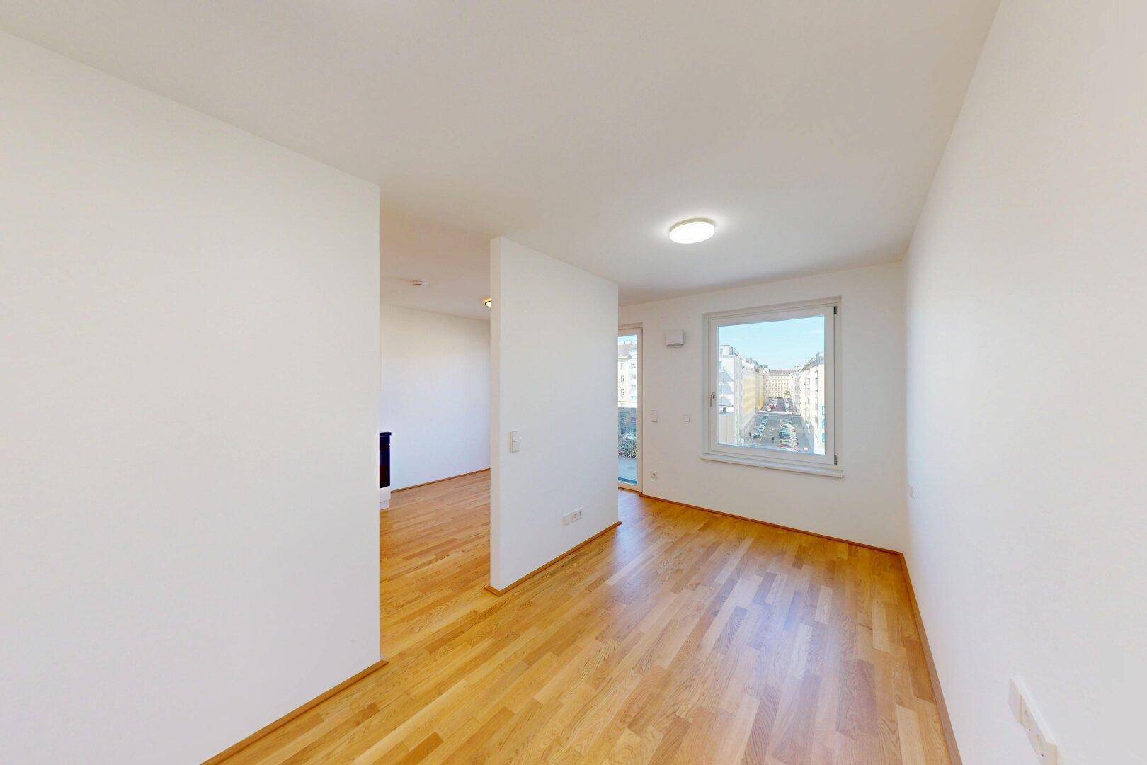 Helles Schlafzimmer mit Parkettboden und einem Fenster mit Stadtblick.