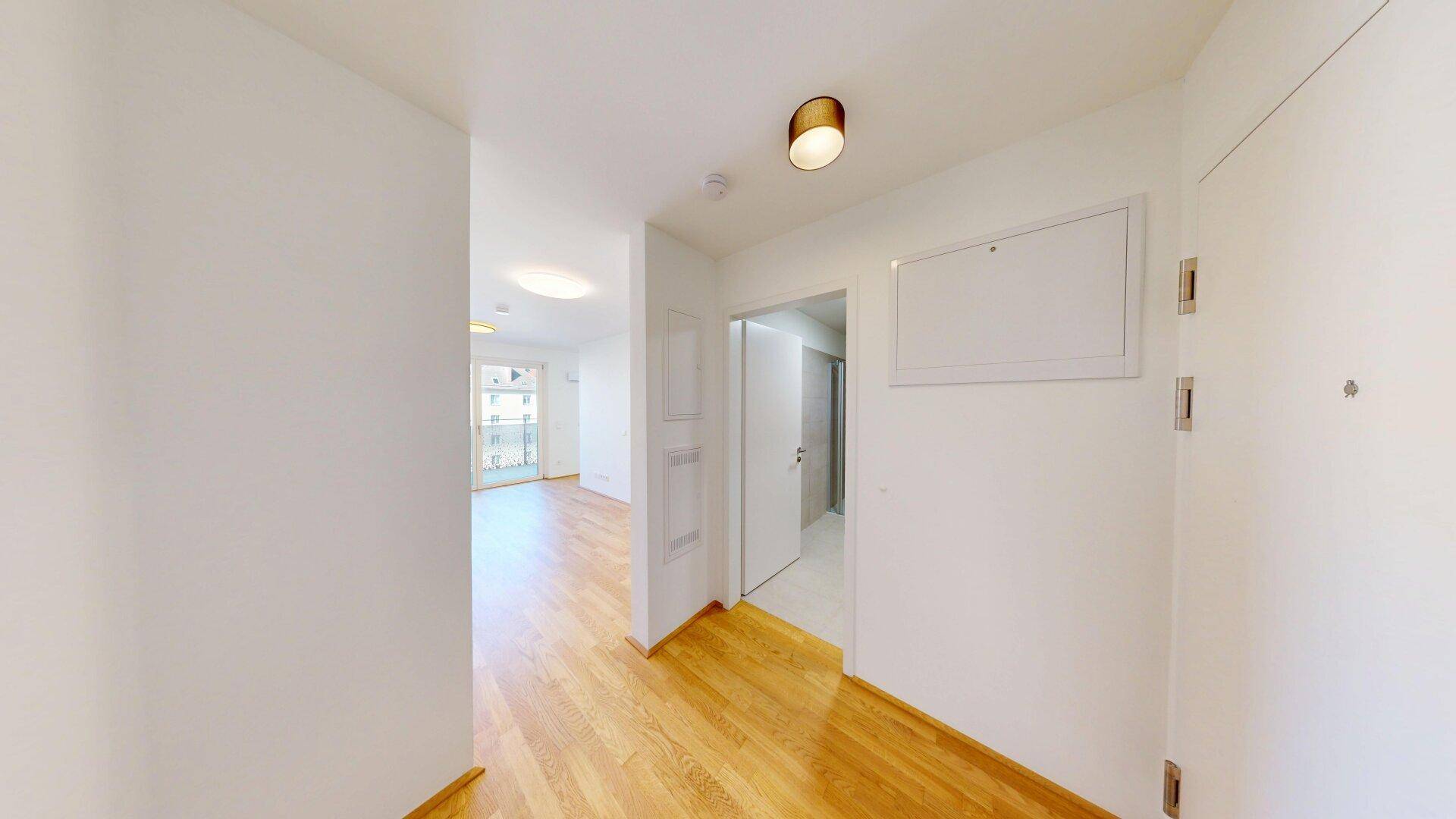 Heller Flur mit Parkettboden, der zu den verschiedenen Räumen der Wohnung führt.