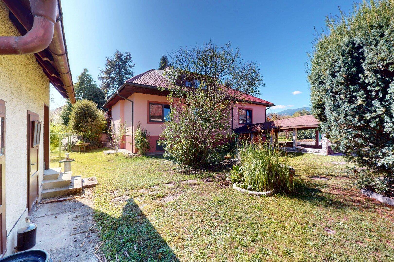 Rückansicht des Hauses mit großem Garten und viel Grünfläche an einem sonnigen Tag.
