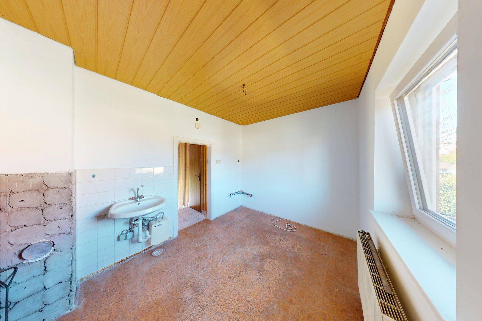 Leerer Raum, möglicherweise eine Küche, mit gelber Holzdecke und Spülbecken.