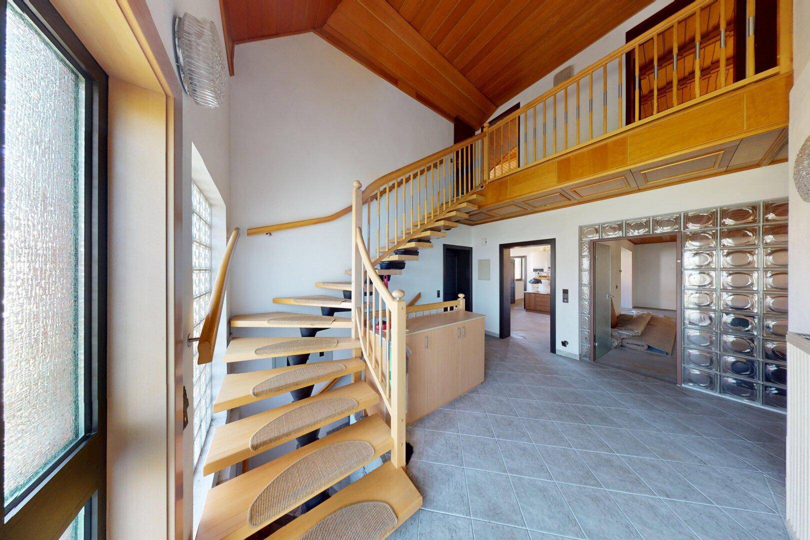 Heller Eingangsbereich mit Wendeltreppe, Holzdecke und Fliesenboden.