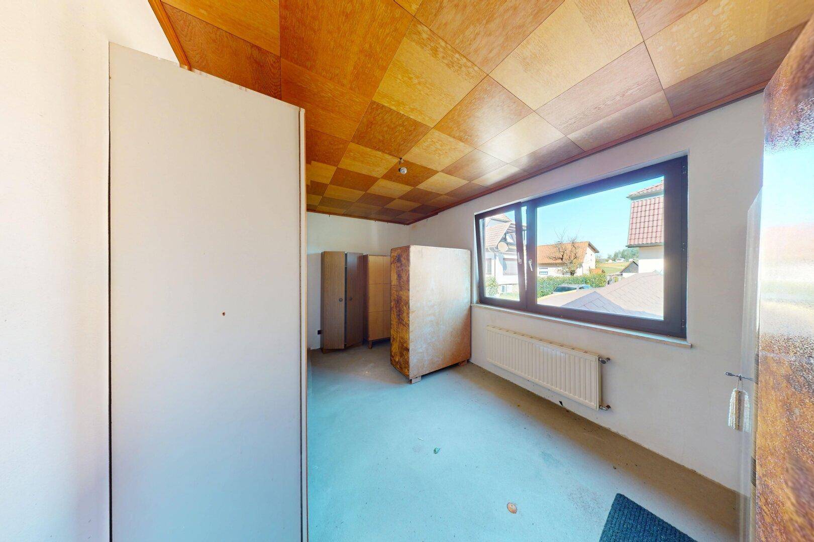 Unmöbliertes Schlafzimmer mit Holzkassettendecke und Heizkörper unter dem Fenster.