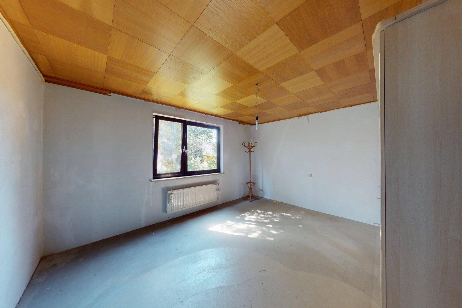 Helles Schlafzimmer mit Holzkassettendecke und Blick auf die Umgebung.