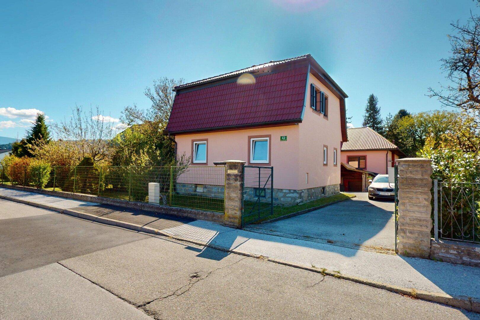 Ansicht des Hauses von der Straße mit gepflegtem Vorgarten und Zaun.