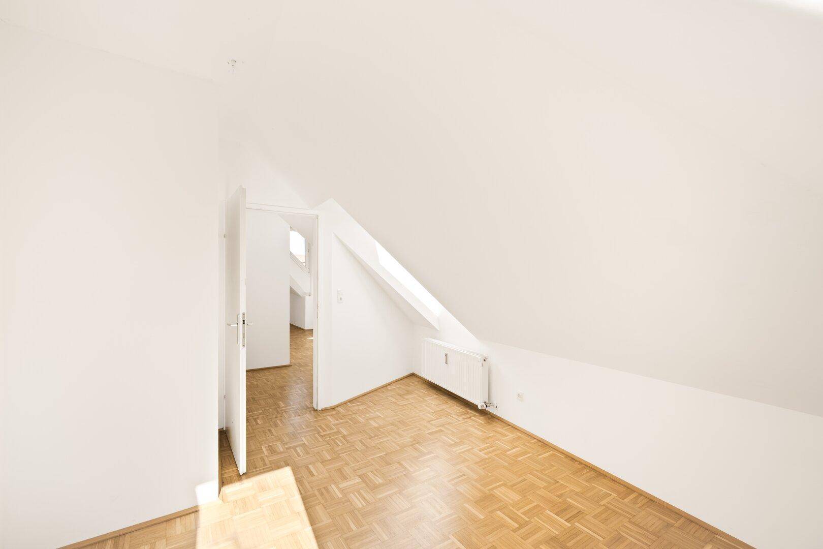 Heller Flur im Dachgeschoss mit Parkettboden und schrägen Wänden.