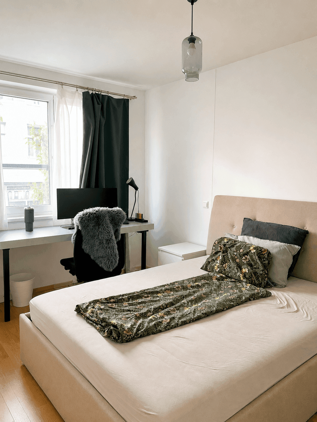 Helles Schlafzimmer mit Doppelbett, Schreibtisch und großem Fenster zur Straße.