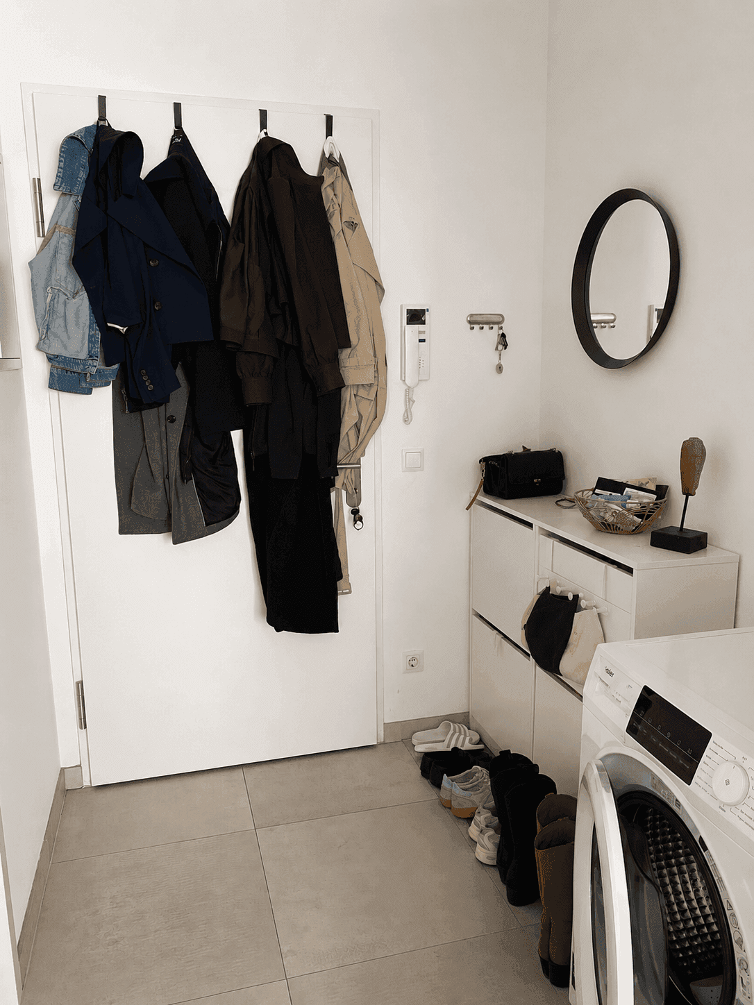 Heller Eingangsbereich mit Garderobe, Schuhschrank und integrierter Waschmaschine.