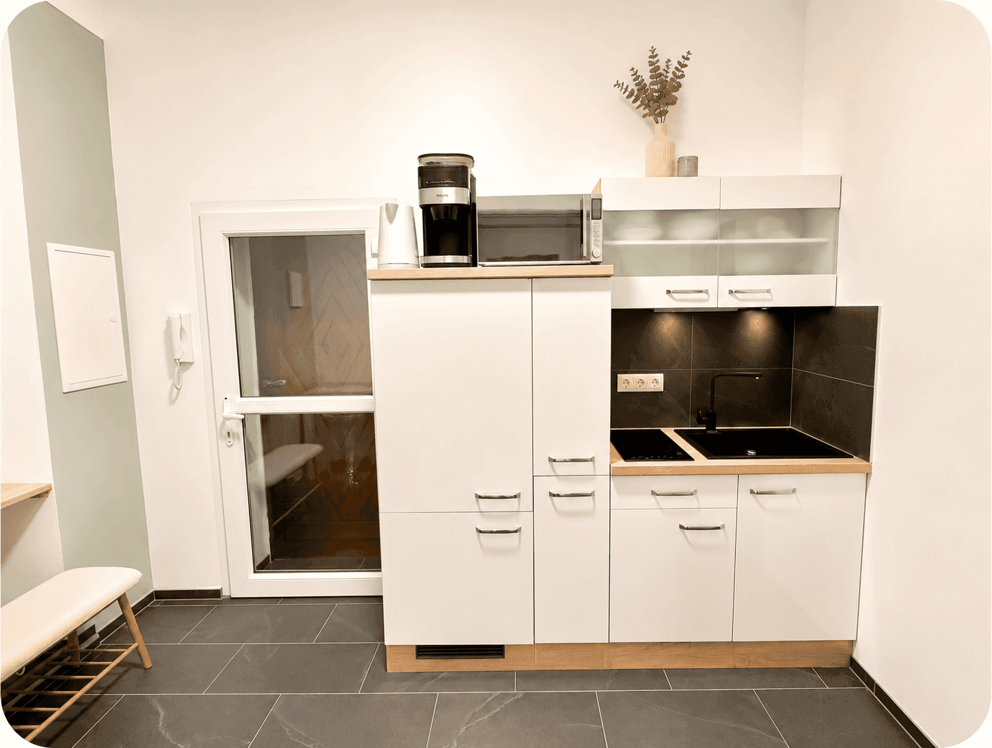 Moderne Küchenzeile mit weißen Schränken, Induktionskochfeld und Kaffeemaschine.