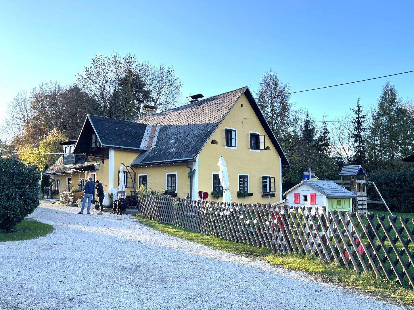 Das charmante gelbe Haus mit traditioneller Architektur, umgeben von einem Garten mit Spielplatz.
