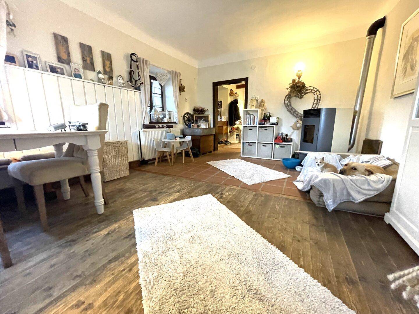Gemütlicher Wohn- und Essbereich mit Holzboden, Kaminofen und rustikalen Details.