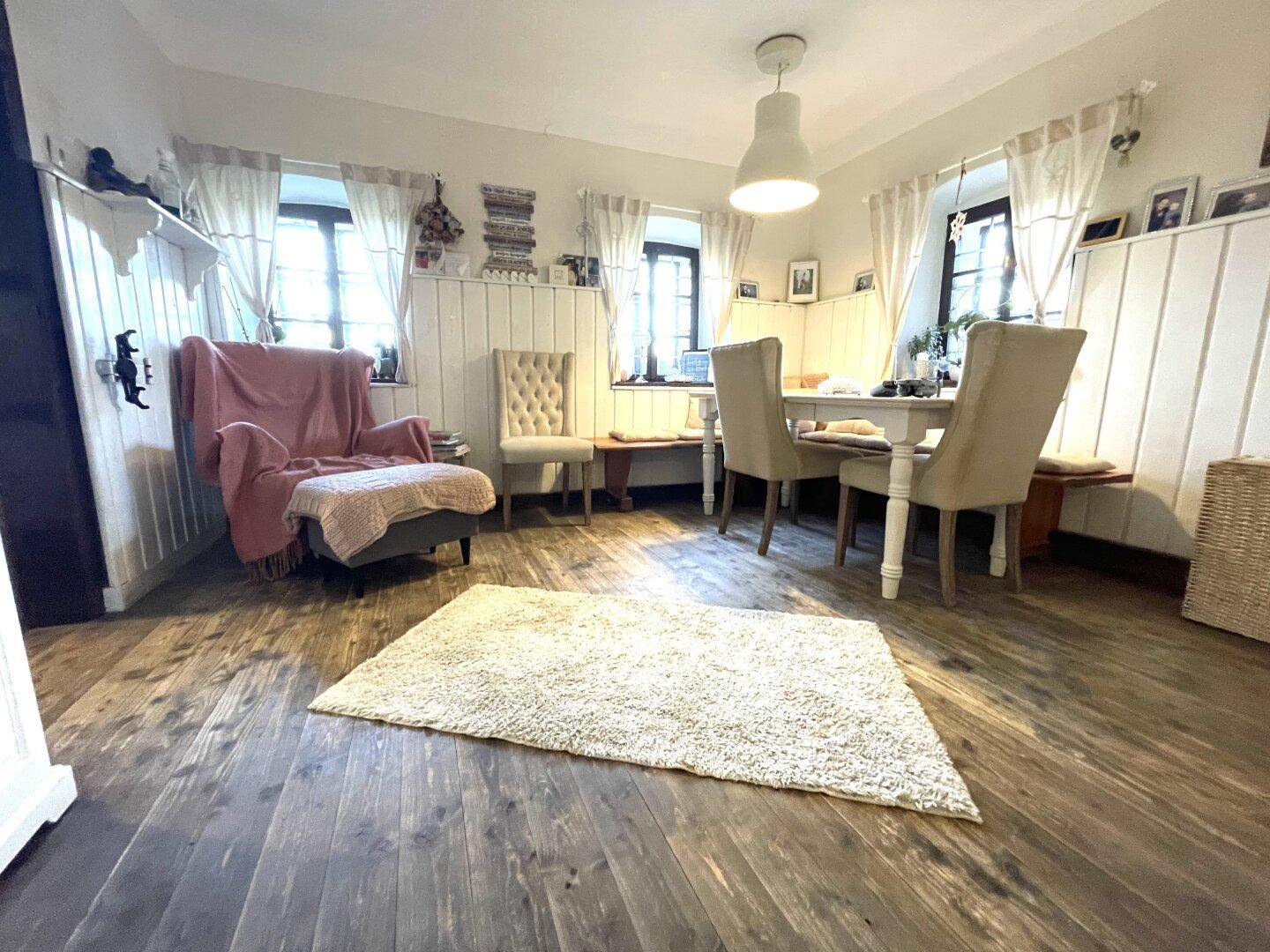 Heller Wohn- und Essbereich mit Holzboden, weißen Wänden und traditionellen Möbeln.