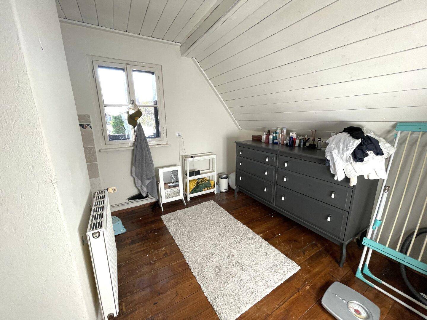 Schlafzimmer im Dachgeschoss mit Holzboden, Dachschräge und Fenster.
