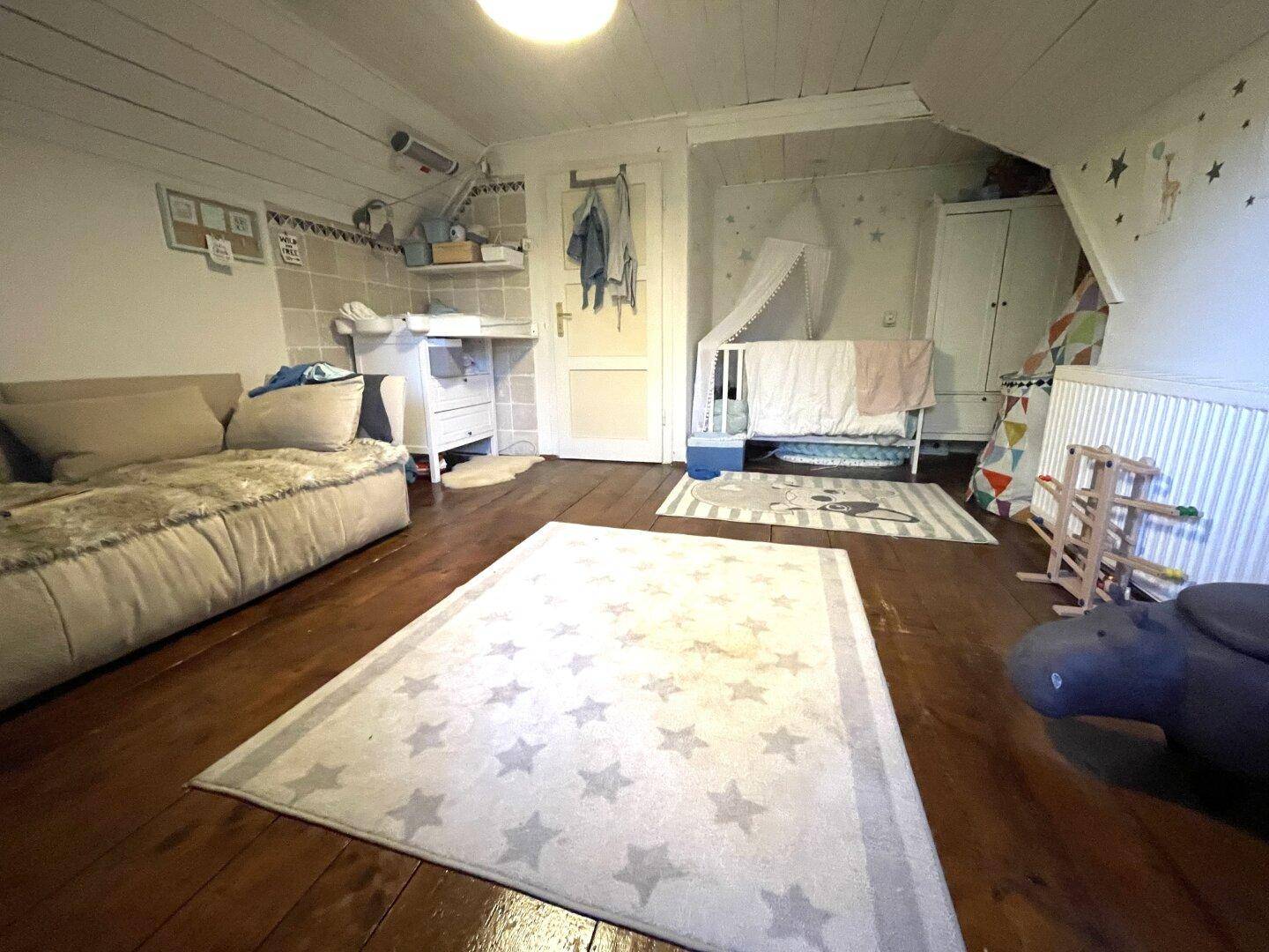Kinderzimmer im Dachgeschoss mit Holzboden, Dachschräge und Babybett.