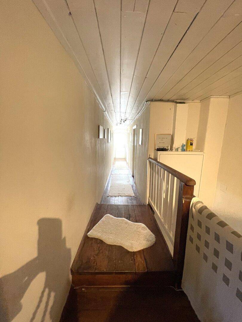 Langer Flur im Dachgeschoss mit Holzboden und Holzdecke.