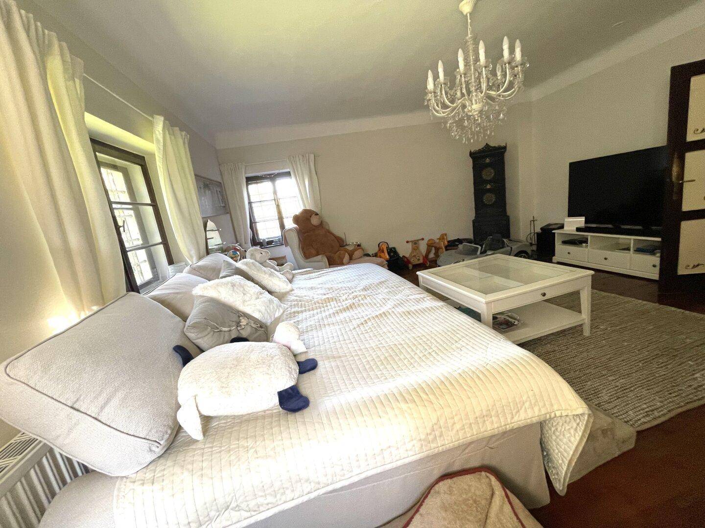Geräumiges Wohnzimmer mit Holzboden, großem Sofa und Kronleuchter.