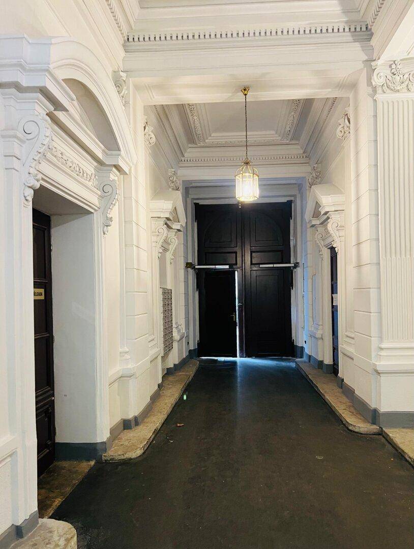Prunkvoller Eingangsbereich eines Altbaus mit hohen Decken, Stuckverzierungen und historischem Charme.