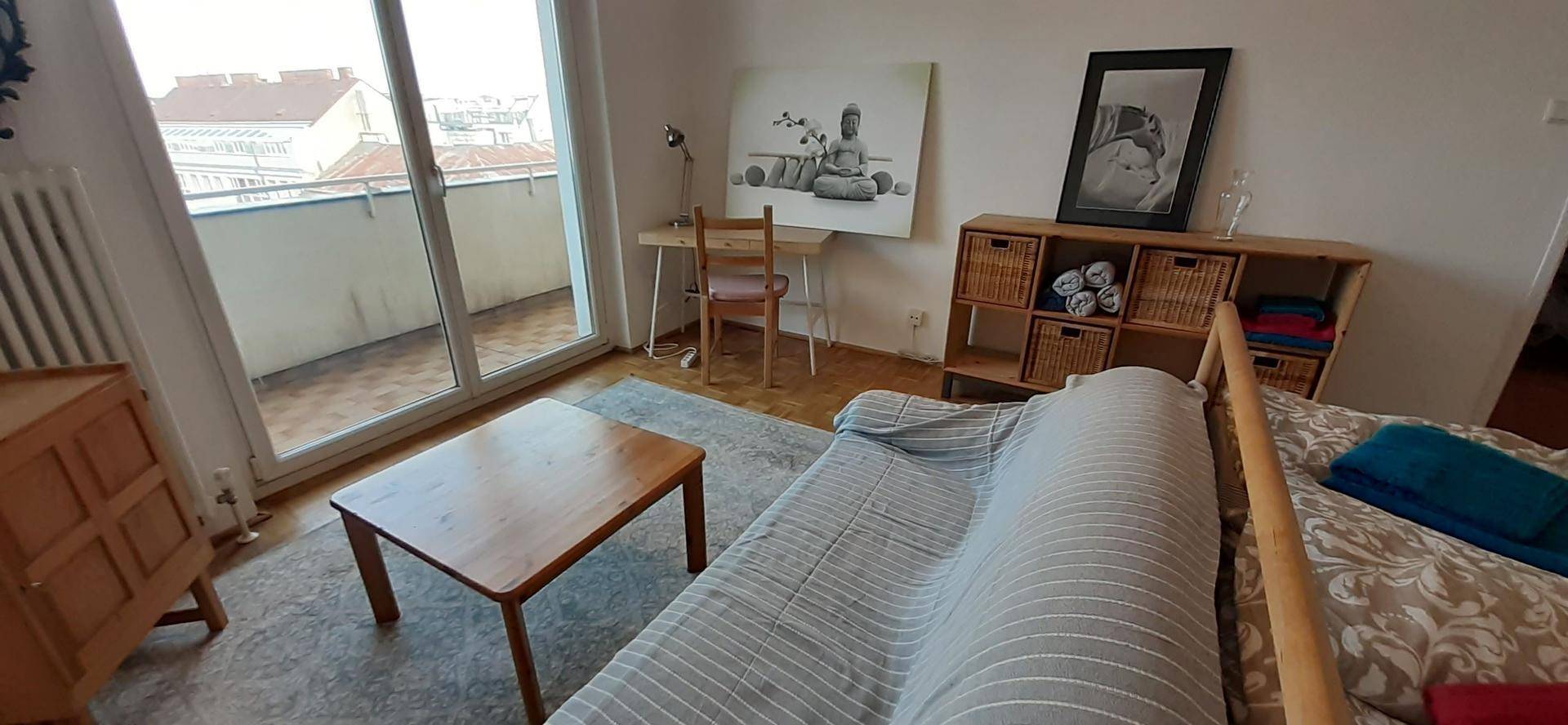 Gemütliches Schlafzimmer mit Teppichboden, Schreibtisch und Blick auf den Balkon.