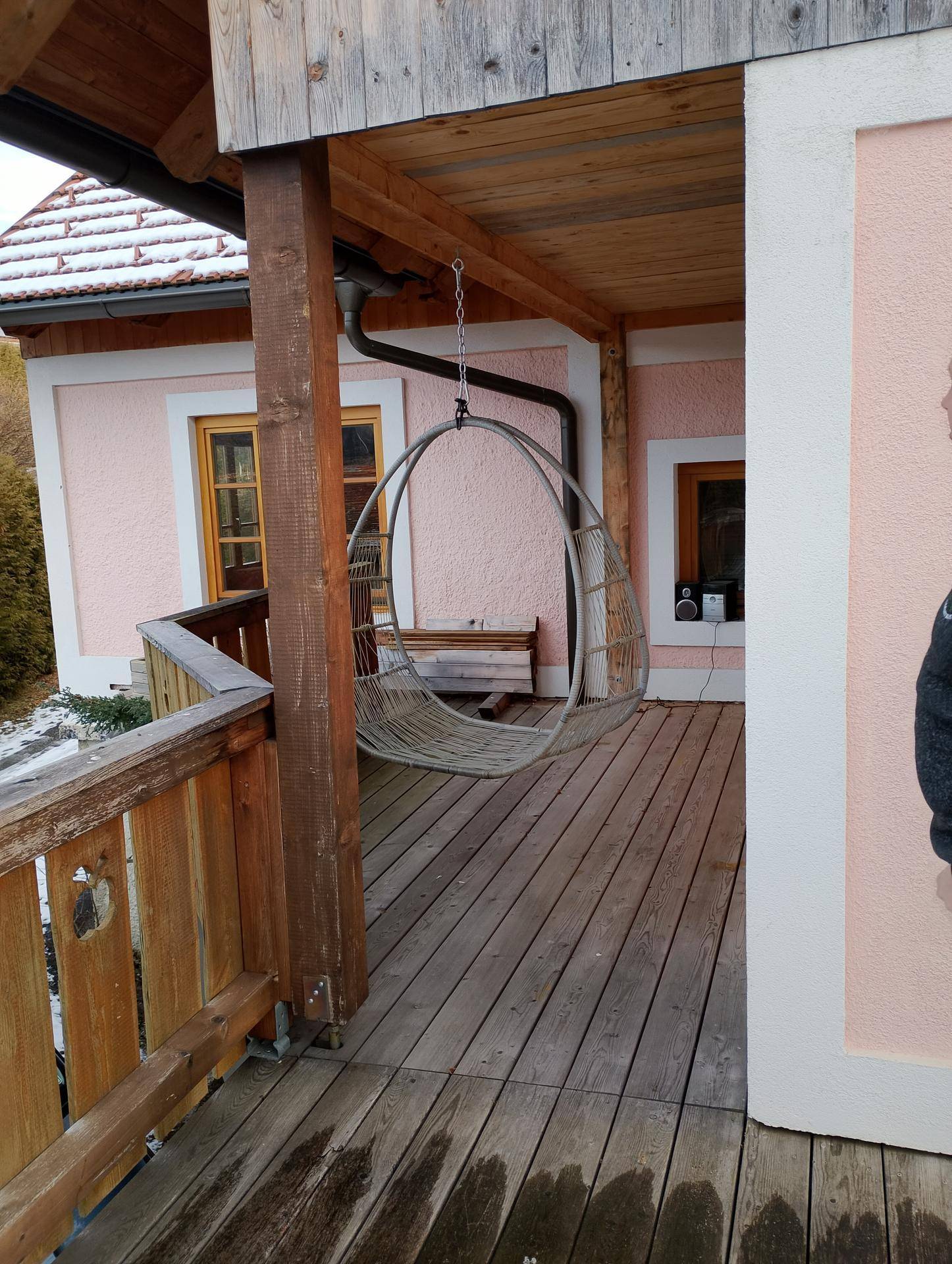 Überdachter Holzbalkon mit Hängesessel und Blick auf die Umgebung.