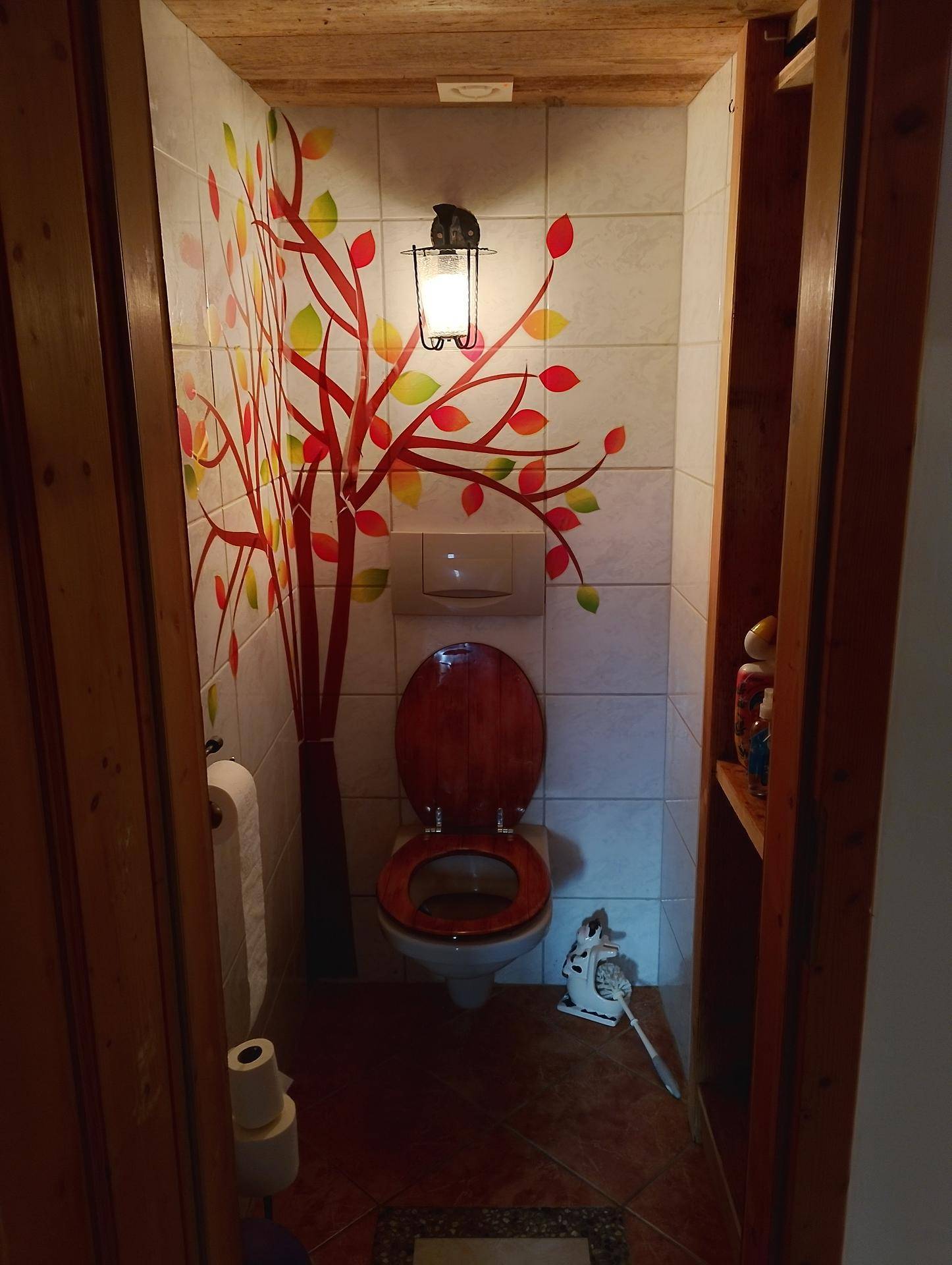 Kleines WC mit Wand-WC, dekorativem Baum-Wandsticker und Holzdecke.