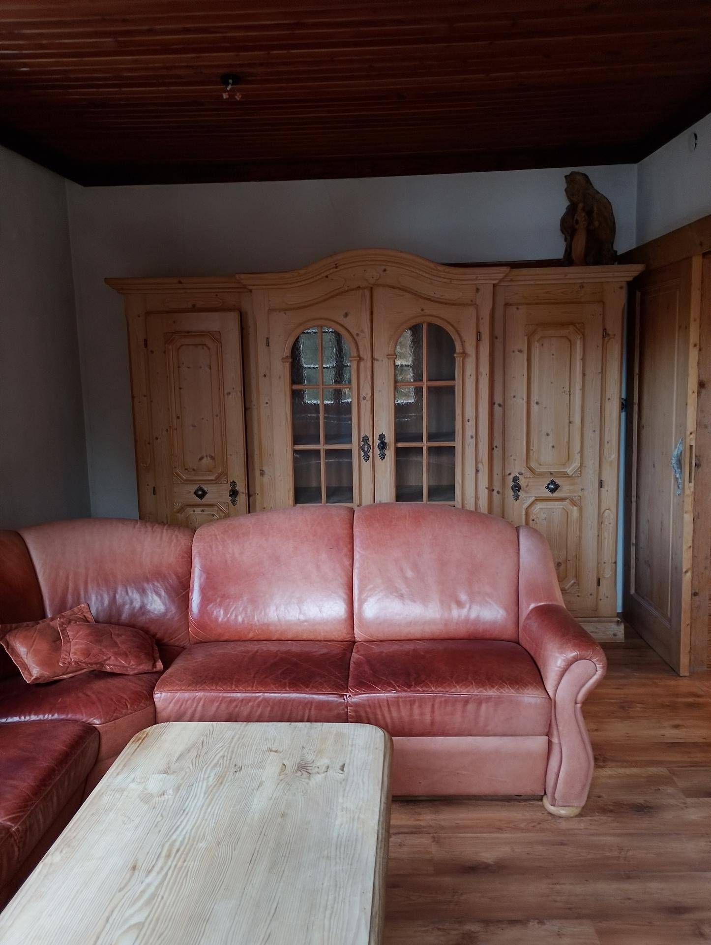 Gemütliches Wohnzimmer mit Ledersofas und einem großen, traditionellen Holzschrank.