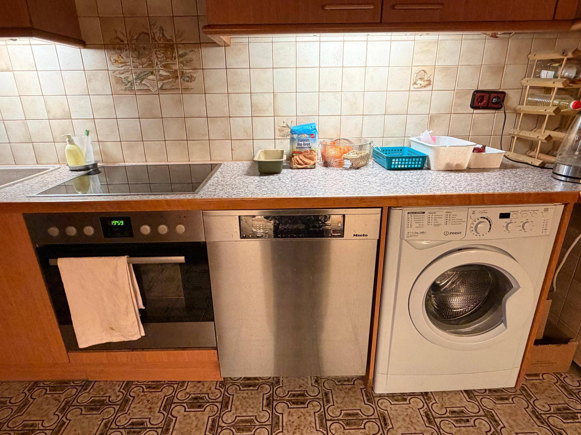 Nahaufnahme der Küchenzeile mit Kochfeld, Backofen, Geschirrspüler und Waschmaschine.