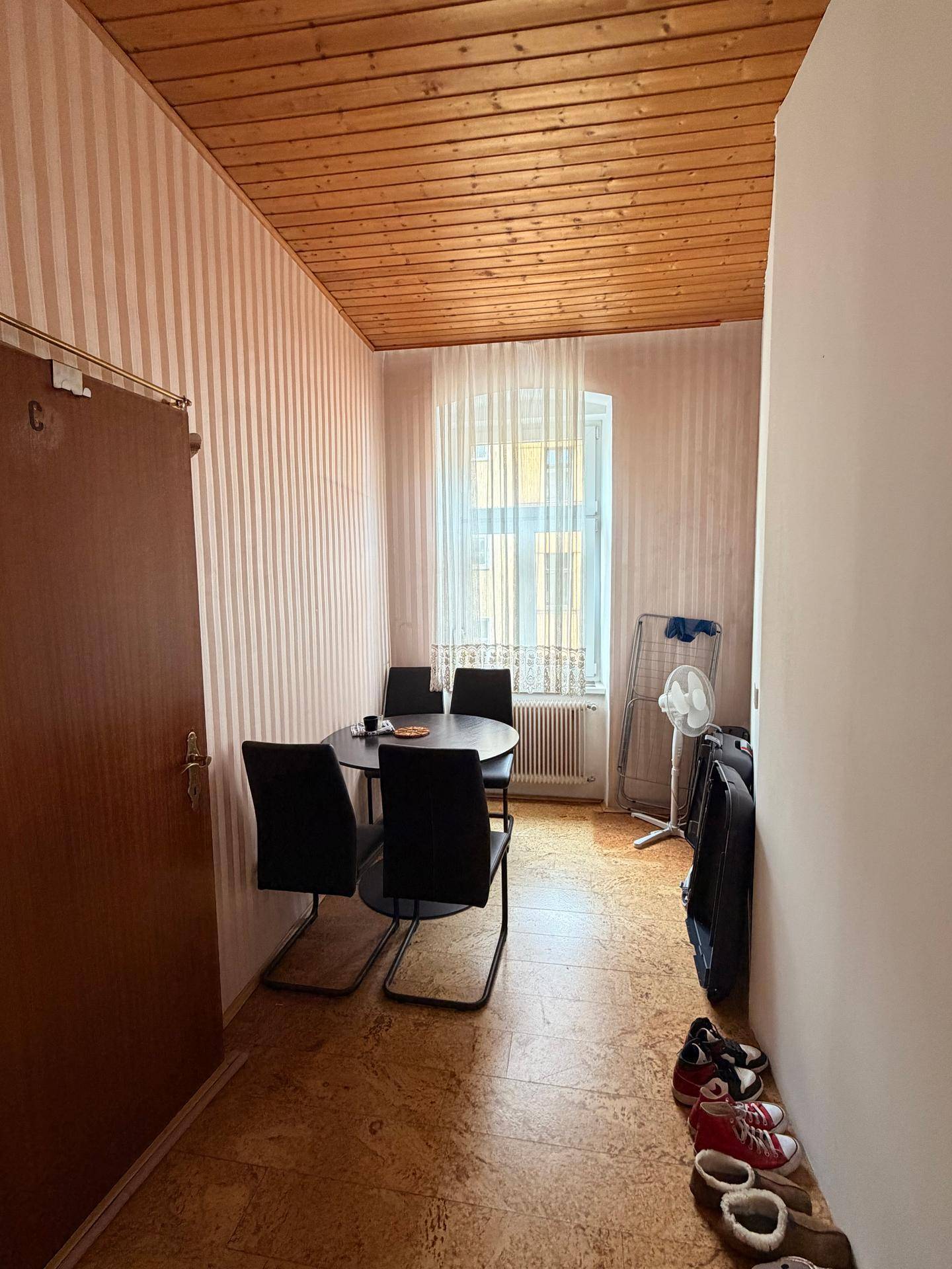Kleiner Essbereich mit Holztisch, vier Stühlen und Holzpaneeldecke in einem Durchgangsbereich.