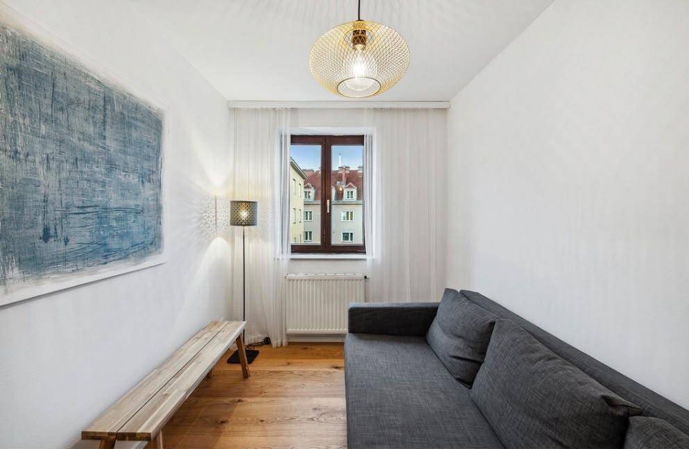 Gemütliches Wohnzimmer mit Sofa, Holzboden und einem Fenster mit Blick auf die Stadt.