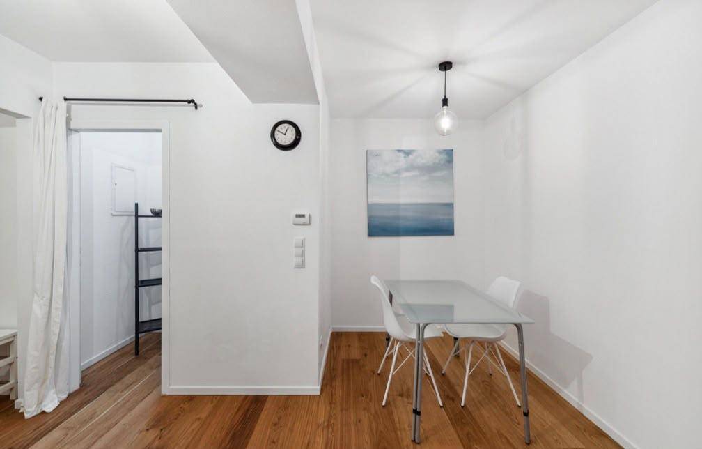 Moderner Essbereich mit kleinem Tisch und Stühlen, ergänzt durch ein abstraktes Kunstwerk an der Wand.
