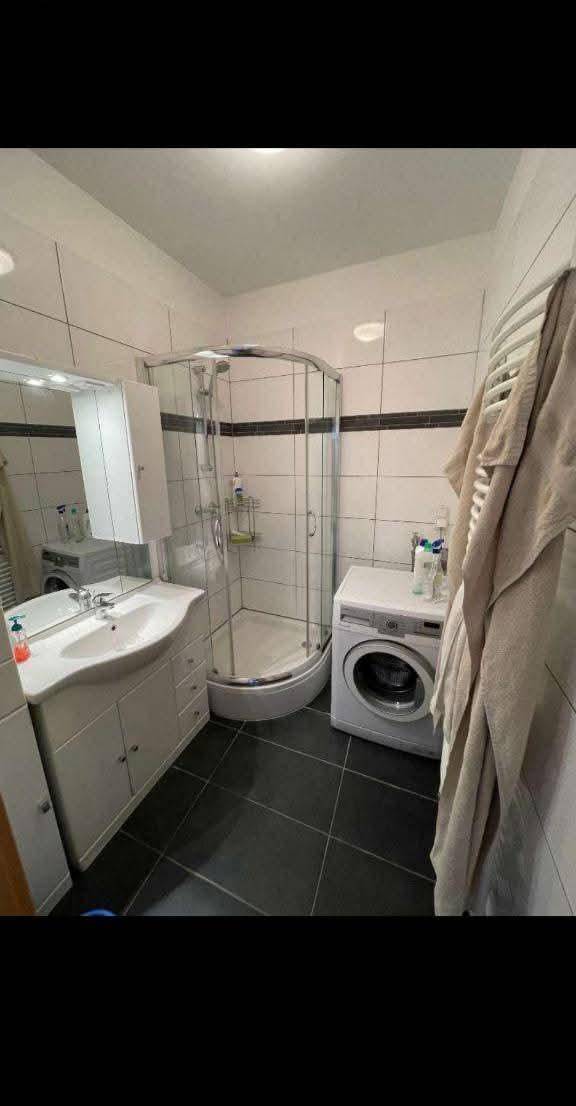 Badezimmer mit Duschkabine, Waschbecken, Waschmaschine und einem praktischen Handtuchheizkörper.